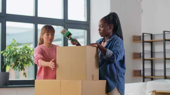 Women with Adhesive Tape Packing Boxes at Home alt