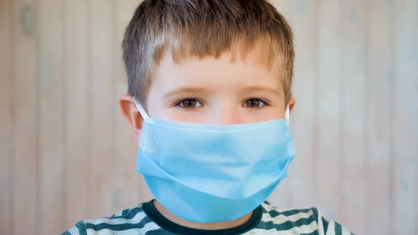 Boy in Medical Facemask Looking at Camera. Coronavirus, Covid-19 Outbreak. Brown Eyes of 6 Years Old