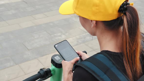 Unrecognizable Woman Scan QR Code By Smart Phone to Unlock and Rent Electric alt