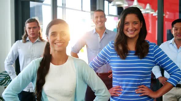 Confident business executives standing with hands on hip in office alt