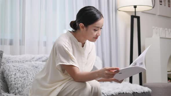 girl sitting on the sofa reading a book, spending time in the living room  alt