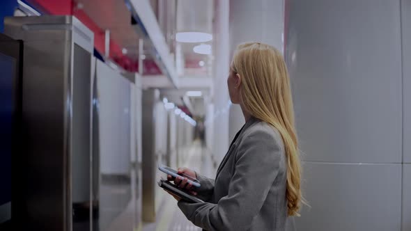 Blonde Girl is Waiting for a Metro Train to Arrive Goes Into the Train alt