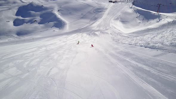 Aerial View Following Two Skiers in Skiing Area on Sunny Day alt