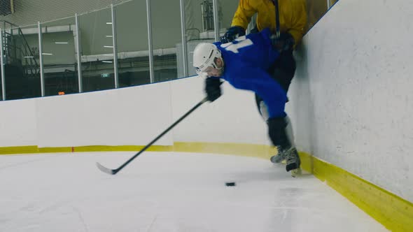 One hockey player pressing another to barrier