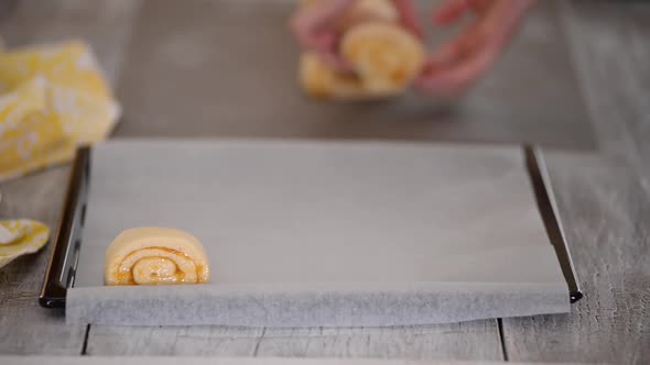 Raw sweet yeast dough on a baking sheet, filling buns jam. Preparation for baking.