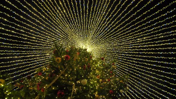 Beautiful Illumination in the Form of a Tent Over the New Year Tree in the City alt