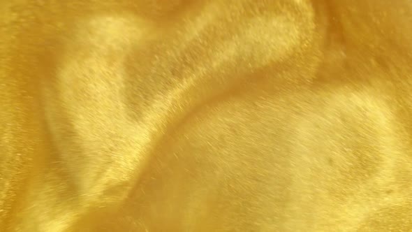 Gold Ink Particles Reacting In Water Creating Abstract Beautiful Background