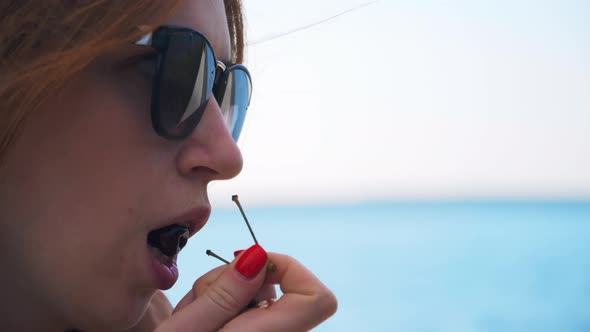 Attractive girl eating cherries from a сup.