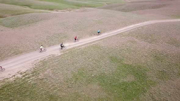 A Group of Cyclists Rides Along the Windmills alt