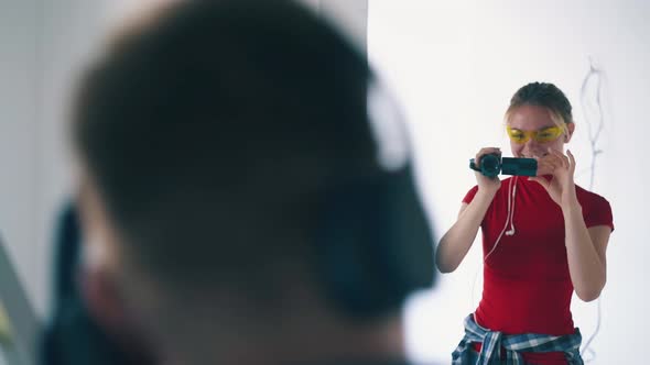 Joyful Girl with Smartphone Shoots Dancing Boyfriend in Room alt