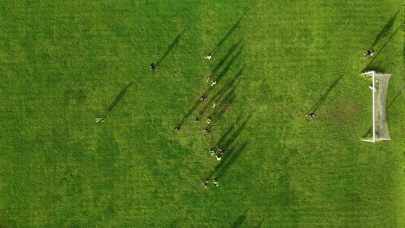 Aerial drone view of a sports field and a football team that practices tactical schemes