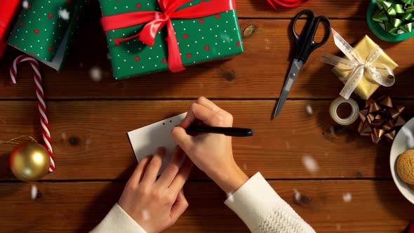 Hands Attaching Name Tag To Christmas Gift alt