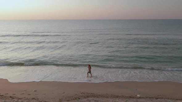 Beautiful Scene of a Woman Walking on Ocean Beach at Sunset.