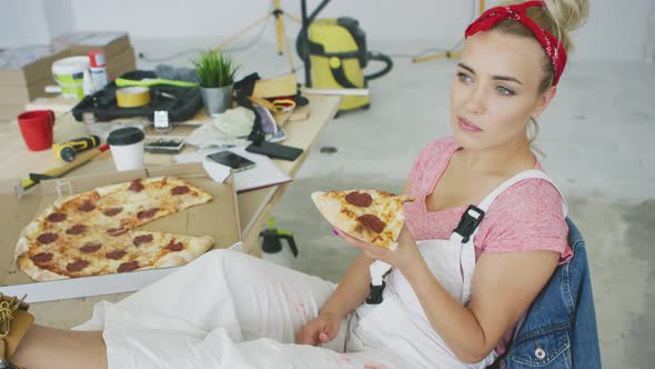 Female Carpenter Eating Pizza at Workplace alt