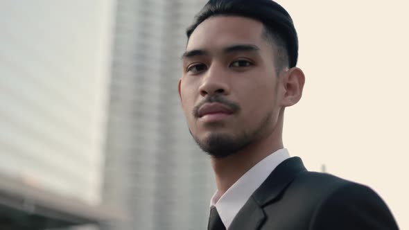 Portrait of a smiling handsome businessman in a black suit while standing outside on the street.