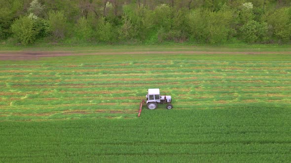 Mowing with a Agriculture Machine Tractor with Mowers on the Big Farm Field alt