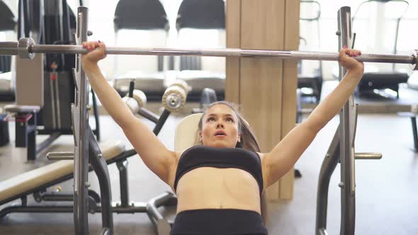 Fit Woman Engaged in the Hall Doing an Exercise Press Barbell