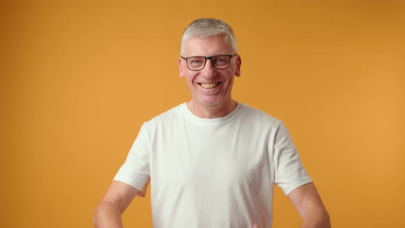 Happy Senior Man Showing Thumbs Up Gesture Against Yellow Background