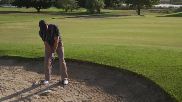 Golf player hitting the ball with his club alt