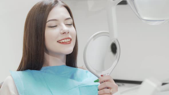 Beautiful Woman Examining Her Teeth in the Mirror at the Dental Clinic alt