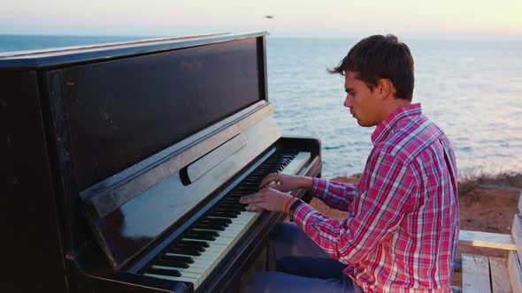 Young Man Playing Melody on Piano on Seashore alt