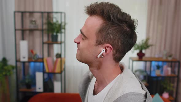 Happy Relaxed Man Wearing Wireless Earphones Dancing Listening Favorite Rock n Roll Music at Home alt