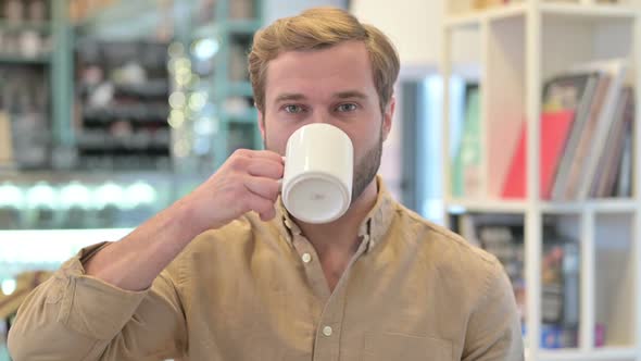 Portrait of Young Man Drinking Coffee and Having Toothache alt