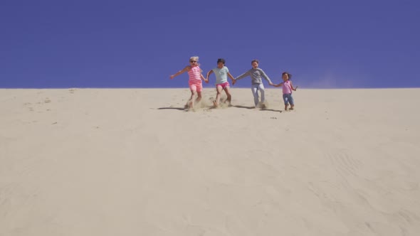 Group of kids running down sand dune at beach