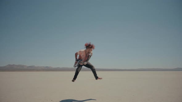 Redhead Barefoot Bloody Musician Plays and Jumps with a Guitar in Desert alt