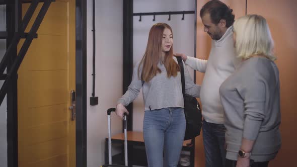 Beautiful Teenage Daughter Hugging Parents Before Going for Trip. Portrait of Charming Caucasian alt