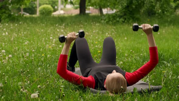 Lifting Hands With Dumbbells Lying On Grass