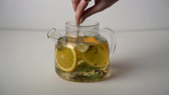 Stir the tea in the glass teapot with a spoon.
