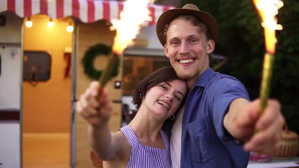 Portrait of a Good Looking Couple Embracing Standing with Sparklers Celebrating Waving Hands with alt
