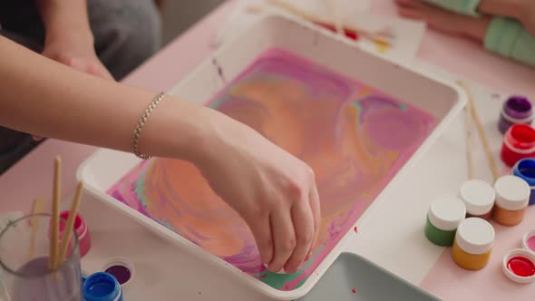 Young Woman Puts Egg Into Tray with Mix for Marbling Design alt