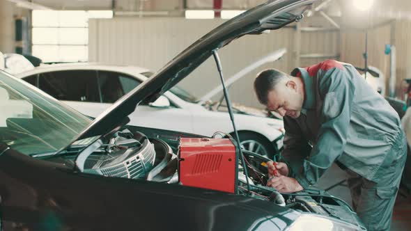 Auto Mechanic Working on Car Diagnostic in a Repair Shop alt