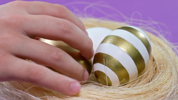 Happy Easter Close Up. Kid Take Golden Egg From The Nest on Purple Background.