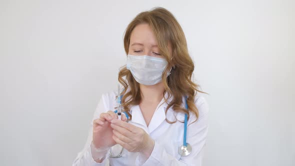 A doctor around his neck holds a medical syringe in his hands before an injection alt