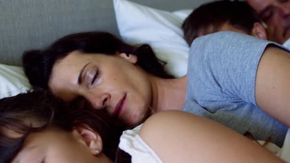 Parents and kids sleeping together on bed in bedroom alt