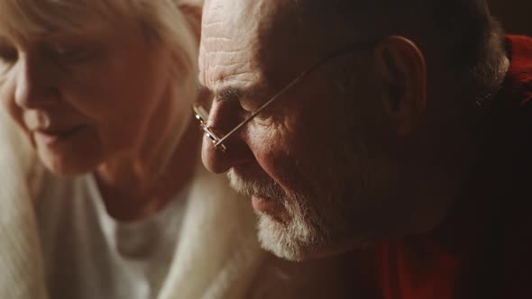 Aged Couple Talking About Photos Together alt