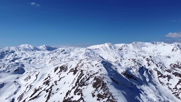 Aerial drone of an amazing panoramic view of a mountain range covered with snow during a sunny day