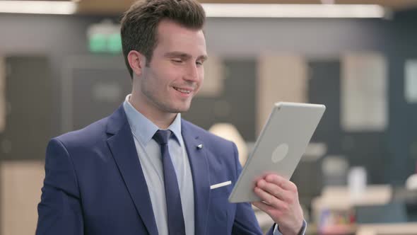 Portrait of Businessman Celebrating on Tablet in Office alt