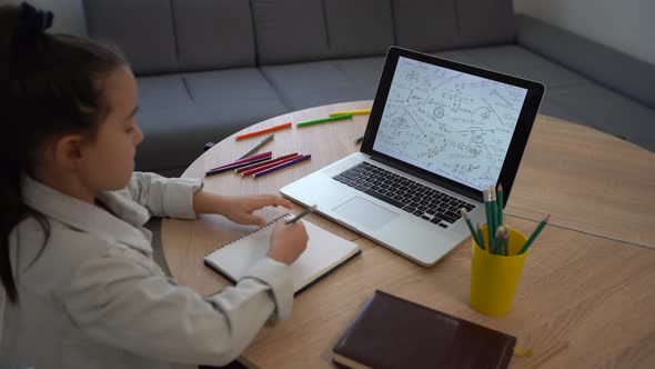 Smart Little Little Girl Learns Online on a Laptop Video Chat at Home Distant Education alt