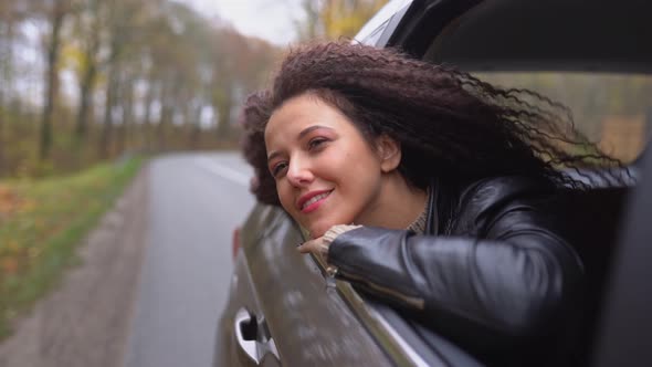 Young afro hair woman travel by car on wild forest autumn roa