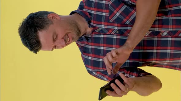 Cheerful Young Man Is Very Delighted with Something Looking on Smartphone.