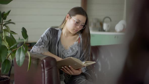 Intelligent Beautiful Asian Woman in Eyeglasses Looking Through Notes in Workbook in Home Office alt