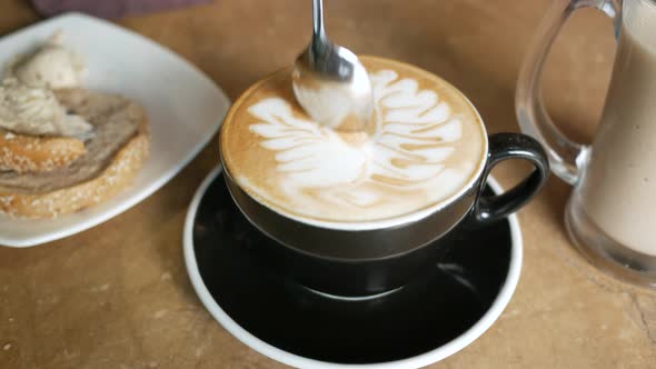 Person Hand Stirring Coffee with Spoon alt