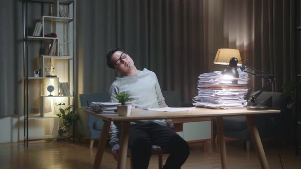 Tired Asian Man Leaning On The Home Chair And Sleeping While Working Hard With Documents alt