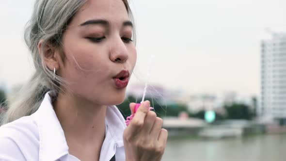 Asian woman playing soap bubbles while standing on the Rama VIII Bridge in Thailand.