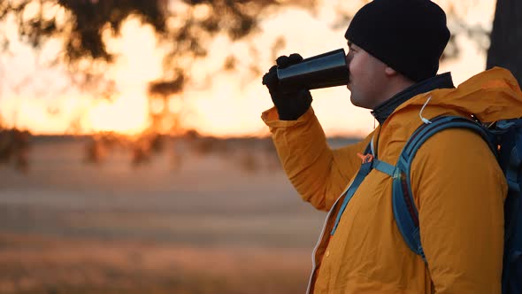 Hiker Young Tourist Enjoying Nature Drinking Hot Tea at Sunset alt