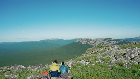 Aerial View of Young Travellers on the Mount Edge with Red Backpack